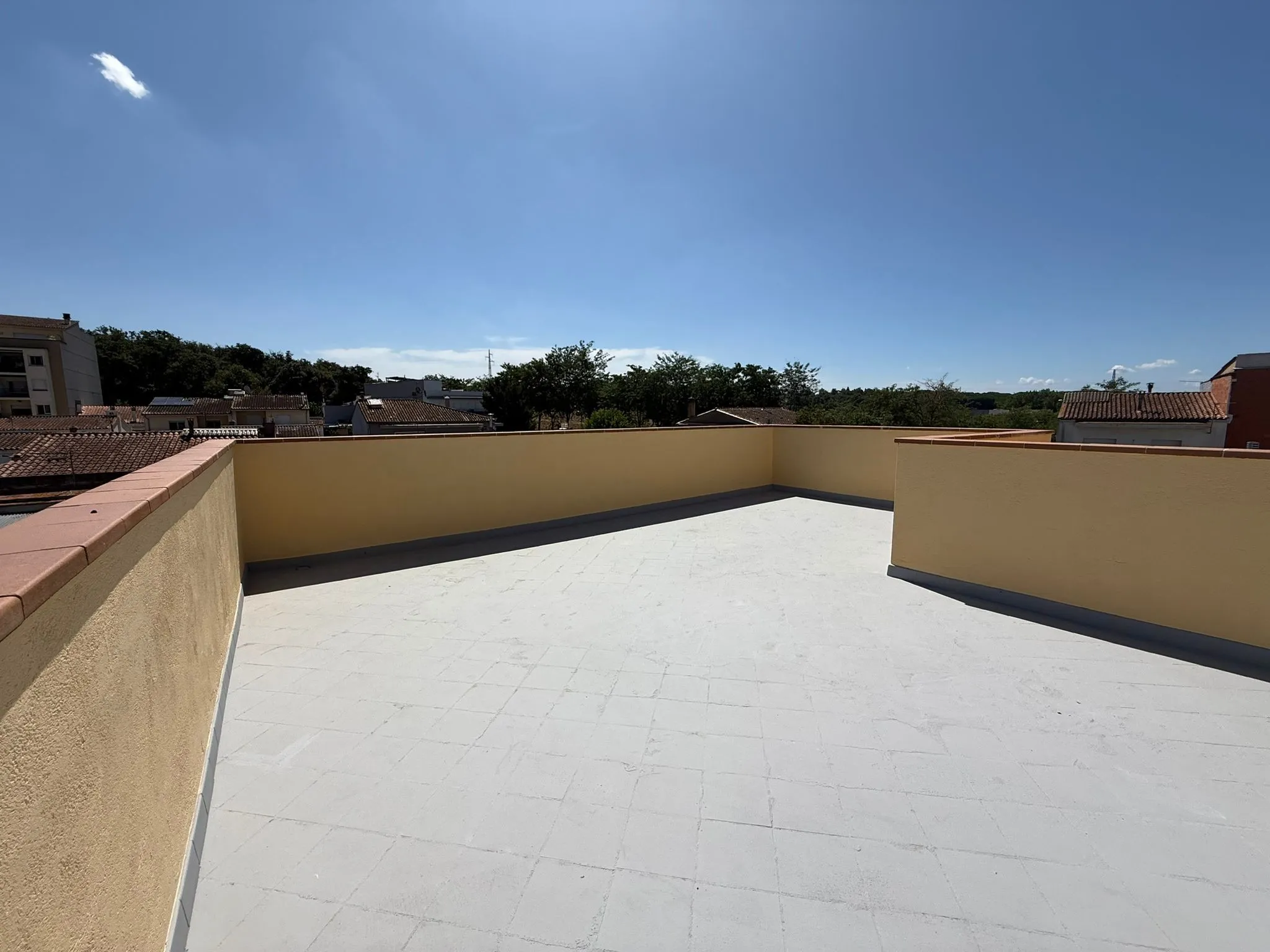 Azotea impermeabilizada y entregada en Girona, Carrer Astúries, con el pretil rematado y vistas a los tejados.