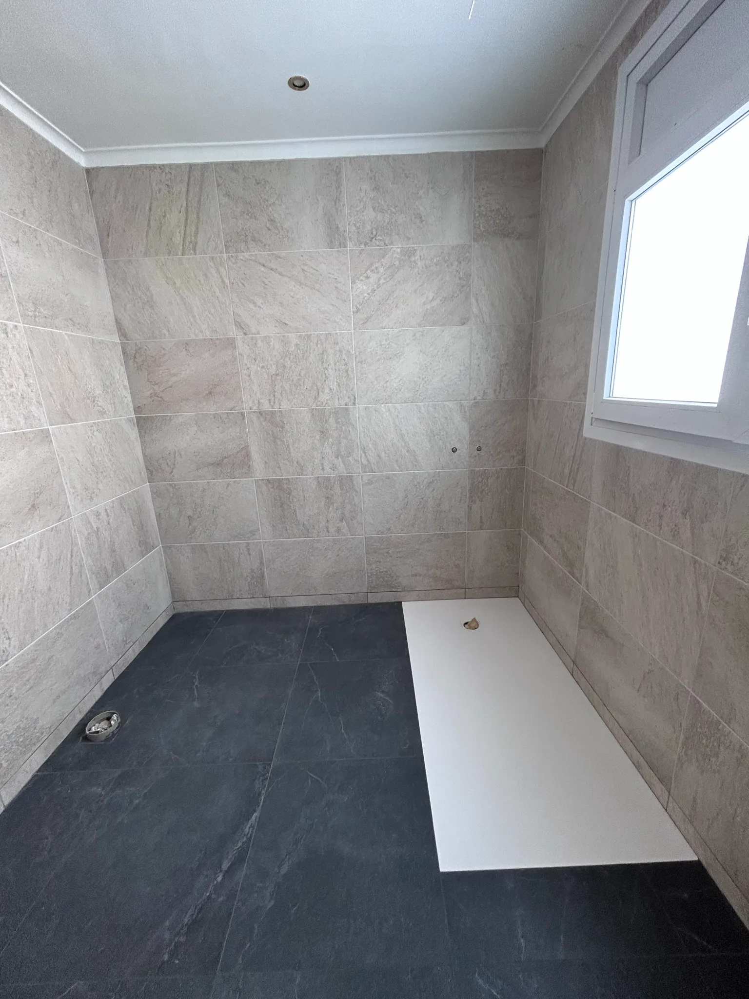 Vista general del baño reformado en Banyoles con porcelánico efecto piedra cálida